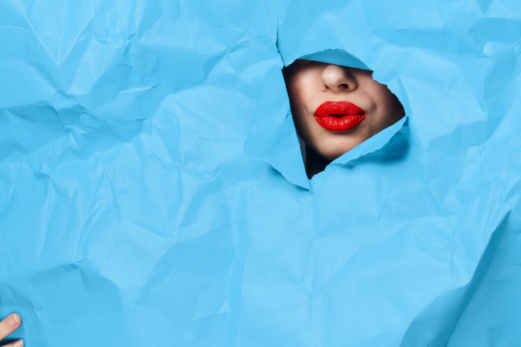 женское лицо прорывается сквозь синий макет крупным планом - Фото, изображение