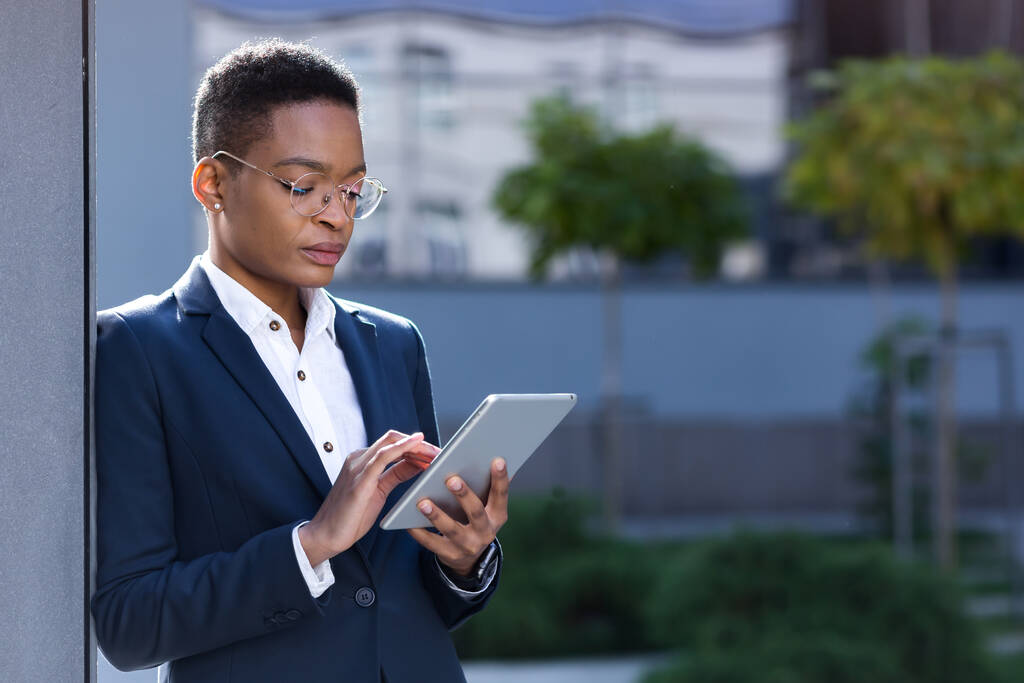 Fiatal sikeres afro-amerikai üzletasszony az iroda közelében használ egy tabletta számítógép, koncentrált és komoly online olvasmányok - Fotó, kép