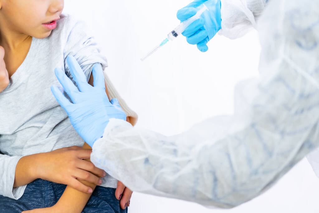 Una doctora calmando al niño con su madre antes de la inyección de la vacuna. Vacunación de niños. Inmunización en la pandemia del coronavirus, covid-19 - Foto, Imagen