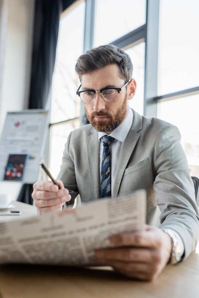 Liikemies silmälaseissa lukemassa sumeaa sanomalehteä virassa  - Valokuva, kuva