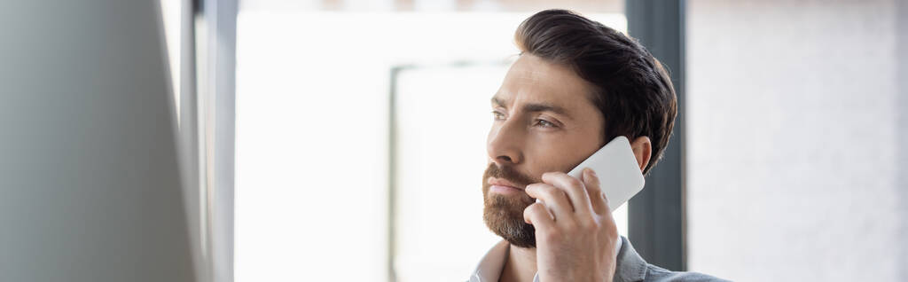 Empresario barbudo hablando en el teléfono inteligente en la oficina, bandera  - Foto, Imagen