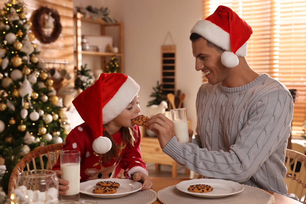 Szczęśliwy ojciec i jego córka jedząc pyszne ciasteczka świąteczne w domu - Zdjęcie, obraz
