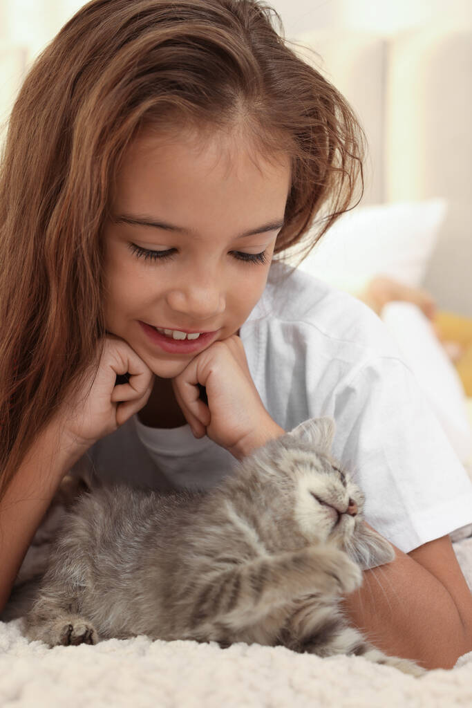 Yatağında kedi yavrusu olan tatlı bir kız. Çocukluk hayvanı. - Fotoğraf, Görsel