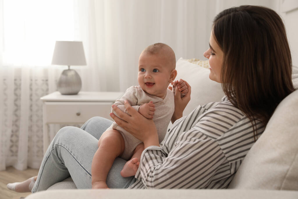 Young woman with her little baby on sofa at home - Photo, Image