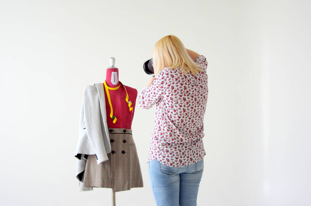 Женщина фотографирует манекен в красивой осенней одежде на белом фоне - Фото, изображение