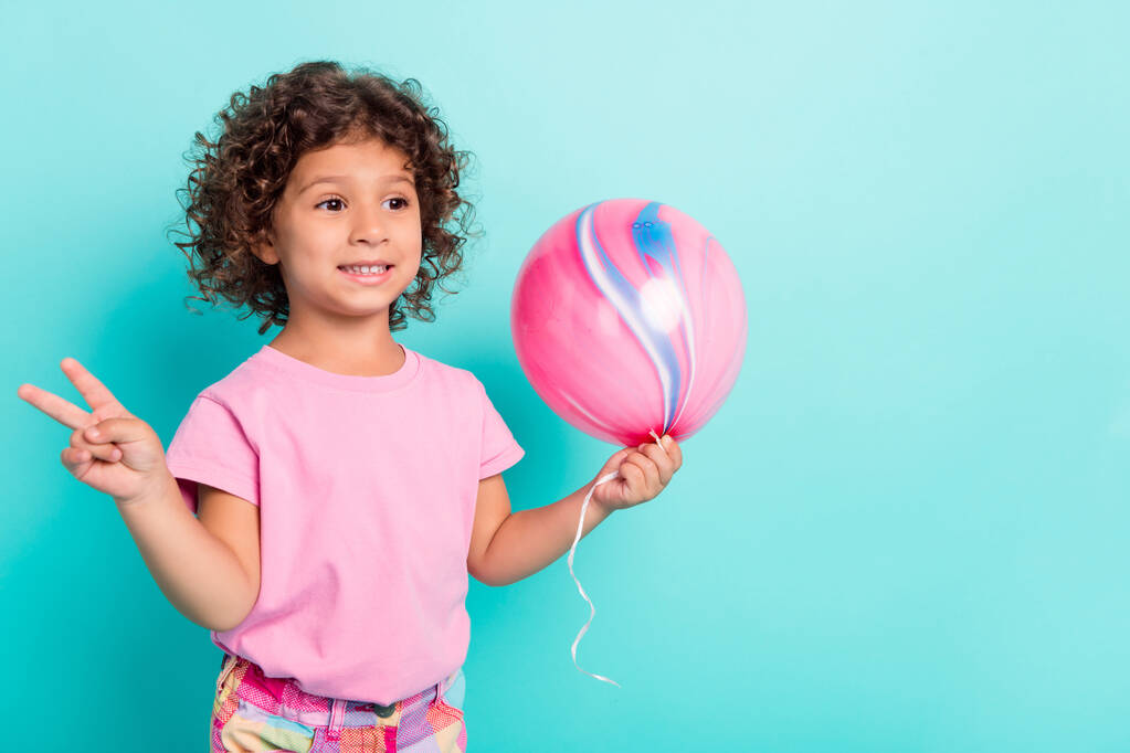 Portrét atraktivní veselá dívka drží vzduchový míč ukazuje V-znamení dobrou náladu izolované přes světlé teal tyrkysové barvy pozadí - Fotografie, Obrázek