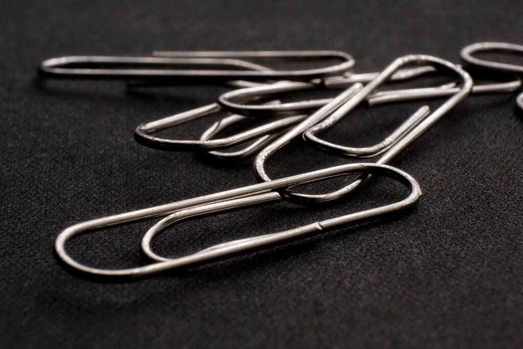A closeup shot of metal paper clips on a dark background - Foto, immagini