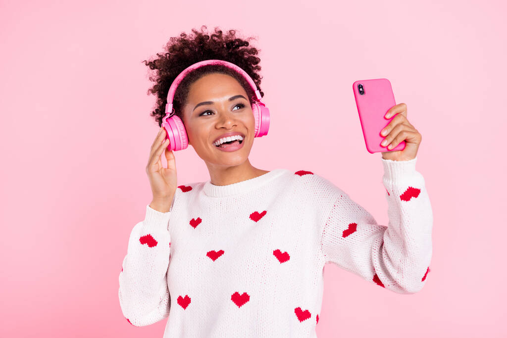 若いアフリカの女の子の写真は楽しい聞くラジオのイヤフォンはピンクの色の背景に隔離された空のスペース使用モバイルに見えます - 写真・画像