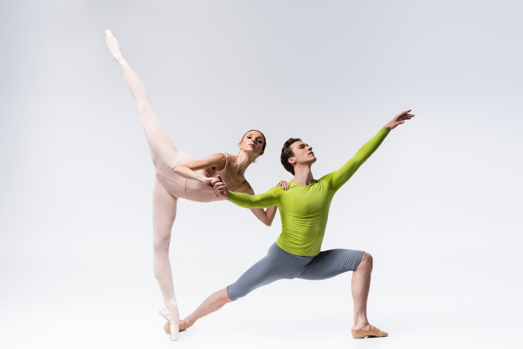 полная длина гибких молодых артистов балета на сером - Фото, изображение