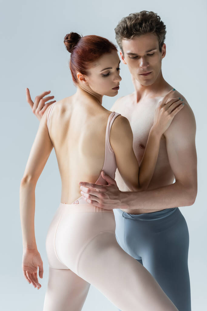 κομψό χορό μπαλαρίνα με shirtless συνεργάτης απομονώνονται σε γκρι - Φωτογραφία, εικόνα