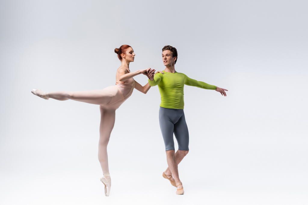 intera lunghezza di eleganti ballerini che eseguono danza classica su grigio - Foto, immagini
