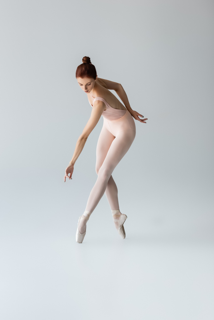 longitud completa de la bailarina sensual en zapatos puntiagudos y body bailando en gris - Foto, imagen
