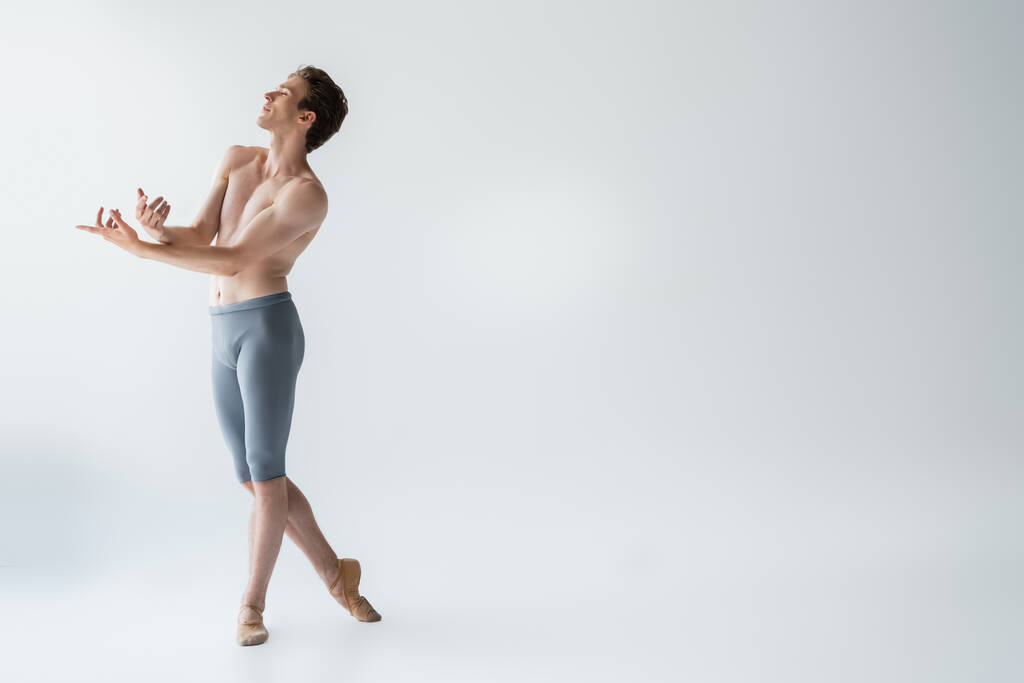ολόσωμος χορευτής μπαλέτου χωρίς πουκάμισο που χορεύει σε γκρι χρώμα  - Φωτογραφία, εικόνα