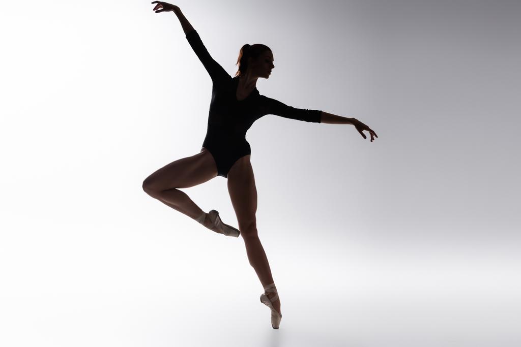 silhueta de bailarina jovem em bodysuit dançando em cinza - Foto, Imagem