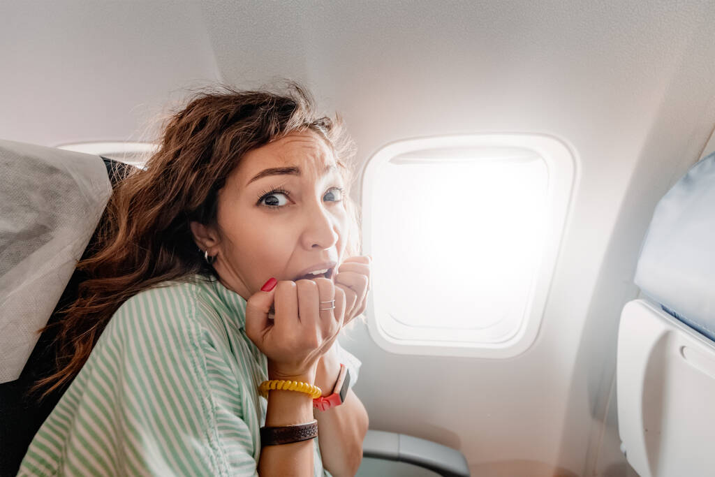Kobieta z aerofobią boi się latać samolotem i doświadcza ataku paniki. Emocje strachu i niepokoju wobec pasażerów - Zdjęcie, obraz