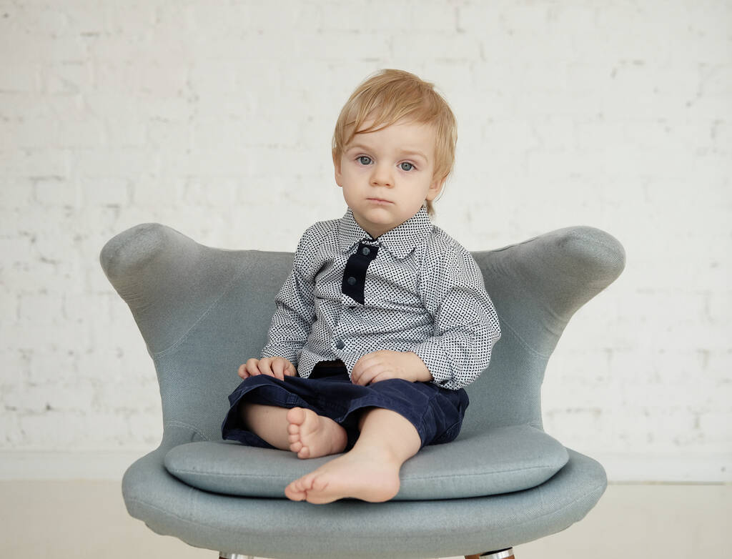 Маленький хлопчик сидить на синьому стільці
 - Фото, зображення