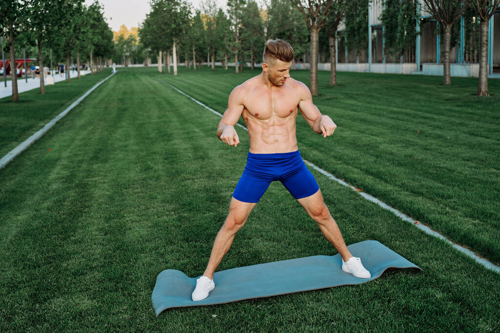 uomo atletico in pantaloncini blu che si allena nel parco - Foto, immagini