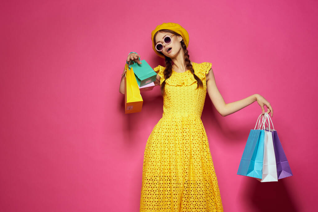 vrolijke vrouw in een gele hoed Shopaholic fashion stijl roze achtergrond - Foto, afbeelding
