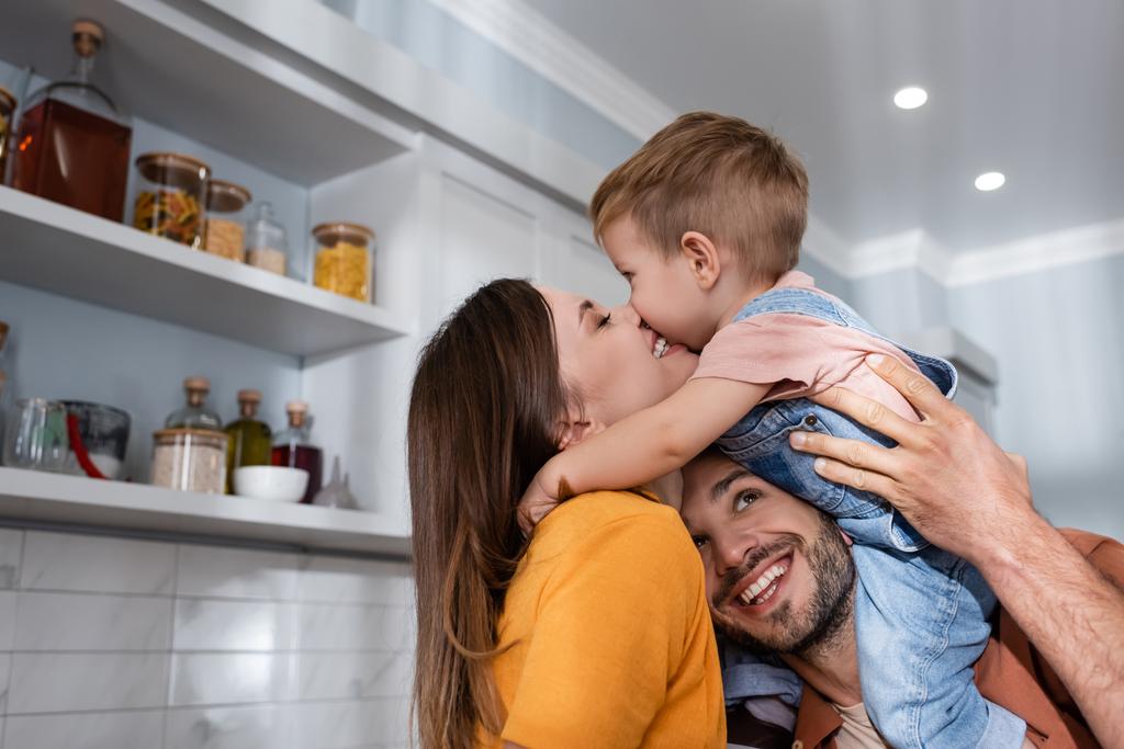 Hymyilevä nainen suutelee poikaa lähellä aviomies kotona  - Valokuva, kuva