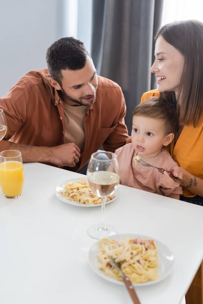 Позитивні батьки сидять біля сина і смачно вечеряють вдома
  - Фото, зображення