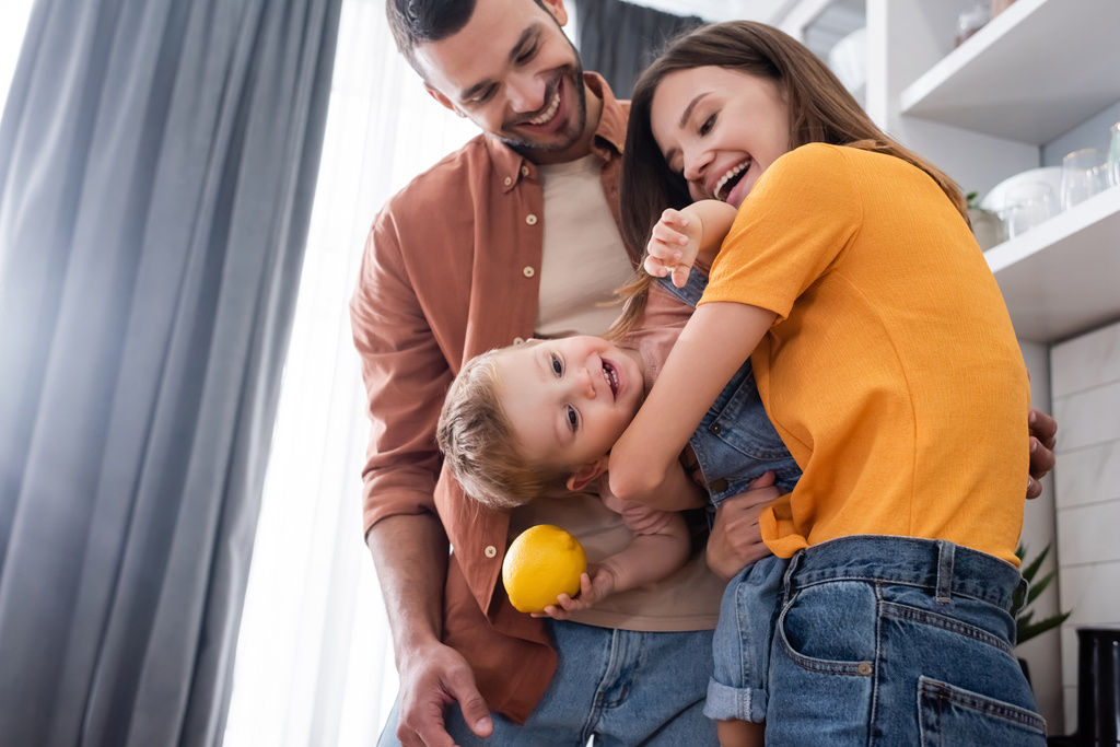 Glückliches Kind hält Zitrone bei Eltern zu Hause  - Foto, Bild