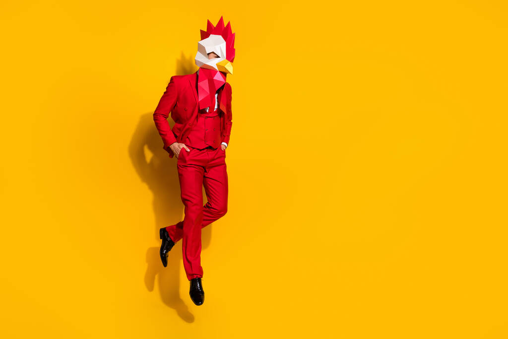 Fénykép őrült őrült fickó ugrás kéz zsebek visel kakas sokszögletű maszk piros szmoking izolált sárga háttér - Fotó, kép