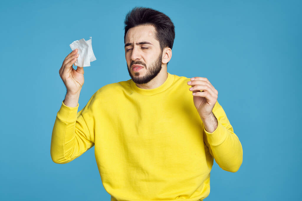 férfi sárga pulóver egészségügyi problémák érzelmek kék háttér - Fotó, kép