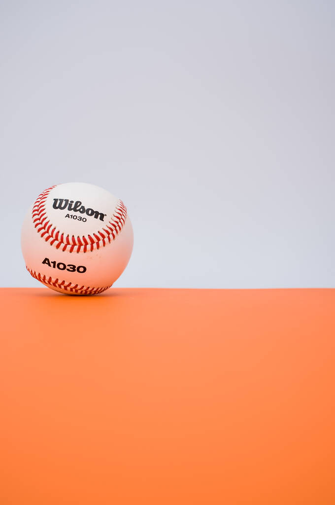INVERIGO, ITALIE - 08 déc. 2021 : balle de baseball isolée sur fond de papier orange avec espace de texte - Photo, image