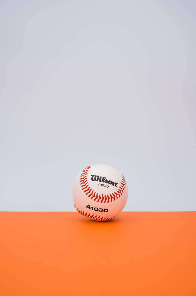 INVERIGO, ITALIA - 08 / 12 / 2021: pelota de béisbol aislada sobre fondo de papel naranja con espacio de texto - Foto, Imagen