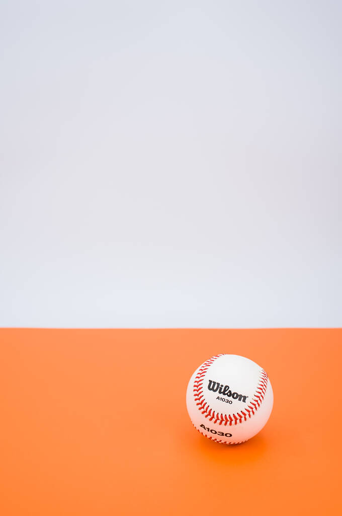 INVERIGO,イタリア- 2021年12月8日:テキスト空間を持つオレンジ色の紙の背景に孤立した野球ボール - 写真・画像