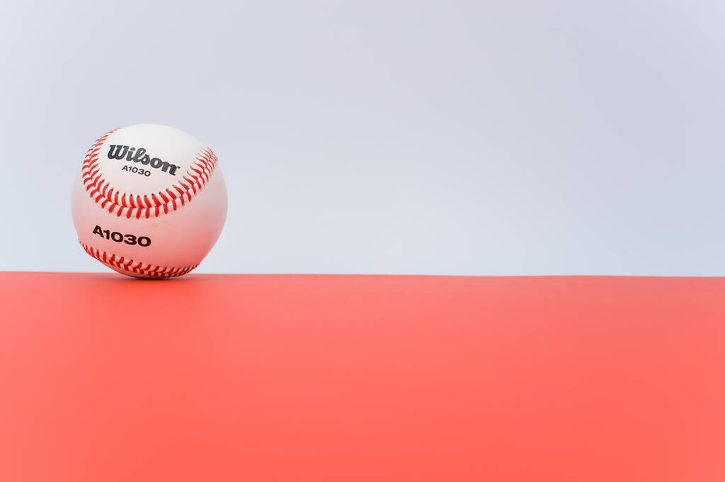 INVERIGO, ITALY - Dec 08, 2021: απομονωμένη μπάλα του μπέιζμπολ σε κόκκινο φόντο με χώρο κειμένου - Φωτογραφία, εικόνα