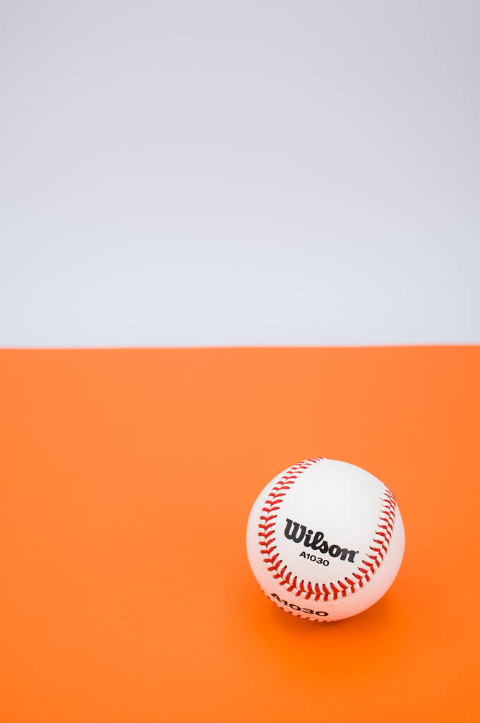 INVERIGO, ITALIE - 08 déc. 2021 : balle de baseball isolée sur fond de papier orange avec espace de texte - Photo, image