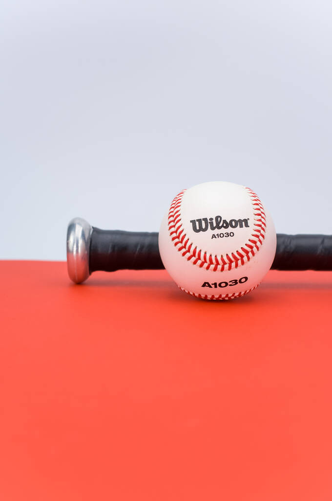 INVERIGO, ITALIEN - 08. Dezember 2021: isolierter Baseballball und Schläger auf rotem Hintergrund mit Leerzeichen - Foto, Bild