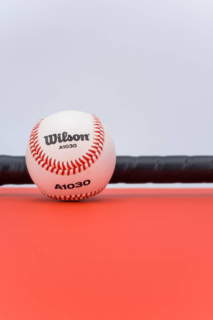 INVERIGO, ITALIEN - 08. Dezember 2021: isolierter Baseballball und Schläger auf rotem Hintergrund mit Leerzeichen - Foto, Bild