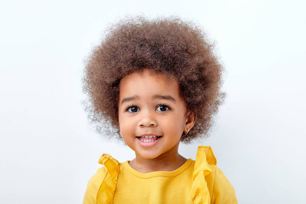 クローズアップ｜ポートレートの美しいアフリカ系アメリカ人の子供とともにふわふわの巻き毛でカメラを見る - 写真・画像
