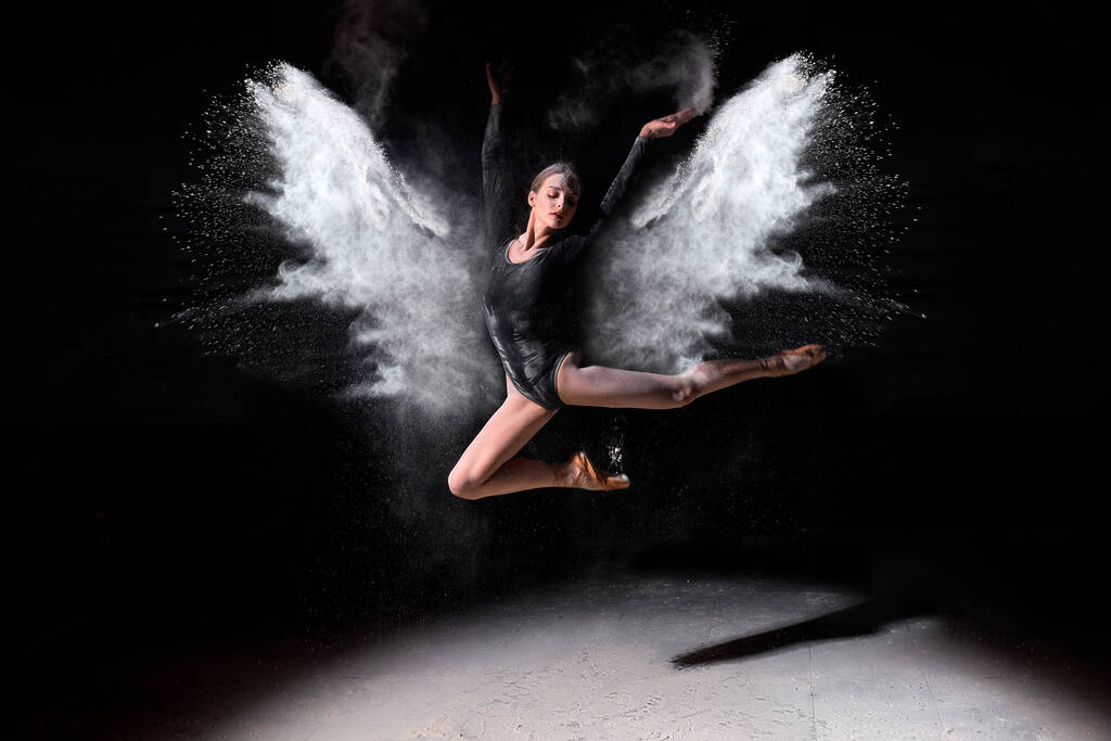 Ballerina Frau im schwarzen Body tanzt wunderschön Ballett im dunklen Studio und springt - Foto, Bild
