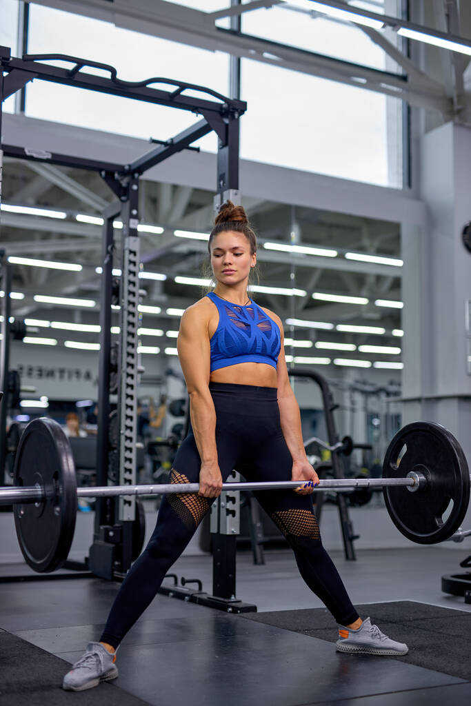 Mujer fuerte en forma joven está haciendo ejercicios con peso en el gimnasio moderno, solo. - Foto, Imagen