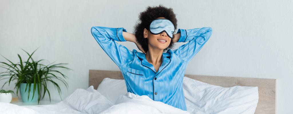 mulher americana africana alegre em pijama e máscara de dormir sentado na cama, banner - Foto, Imagem