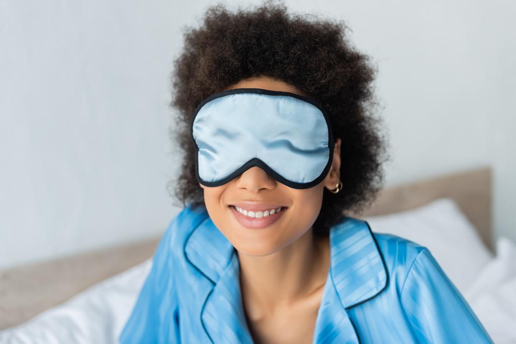 alegre africana americana mujer en azul pijama y seda dormir máscara - Foto, Imagen