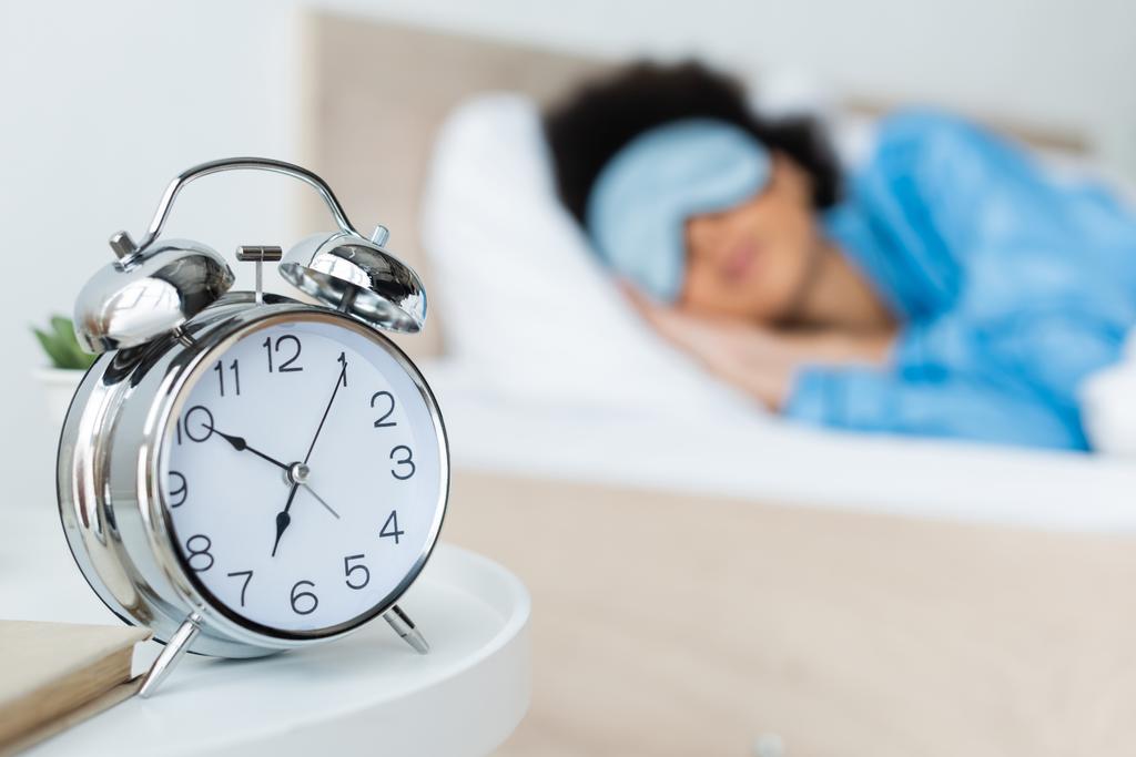 アフリカ系アメリカ人女性のベッドの近くの目覚まし時計 - 写真・画像