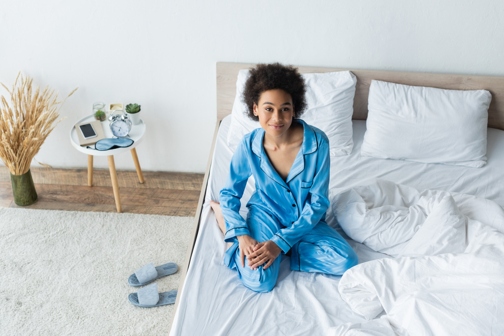 Pijamalı mutlu Afrikalı Amerikalı kadının yatak odasındaki kameraya baktığı yüksek açı.  - Fotoğraf, Görsel