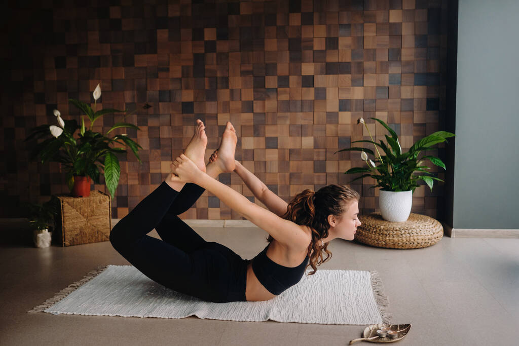 Uma jovem mulher de roupas pretas está fazendo ioga em uma academia moderna.O conceito de saúde. - Foto, Imagem