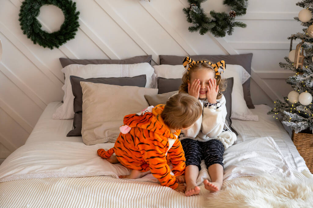Ein Junge und ein Mädchen im Tigerjungen-Kostüm spielen auf dem Bett. - Foto, Bild
