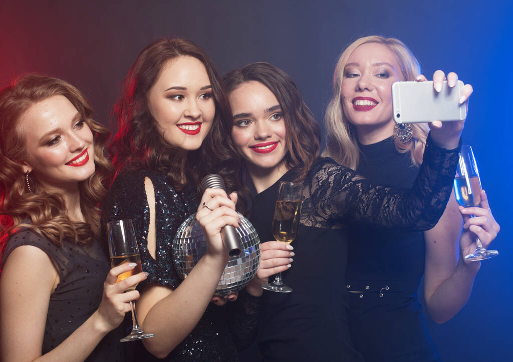 Közelkép a csoport nevető nők visel fekete ruhák bulizás, selfie okostelefonnal - Fotó, kép
