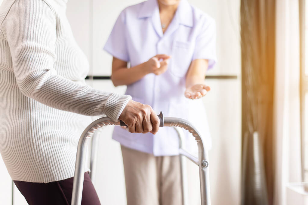 Verpleegster helpen senior vrouw hand houden walker proberen te lopen, Care verpleeghuis concept - Foto, afbeelding