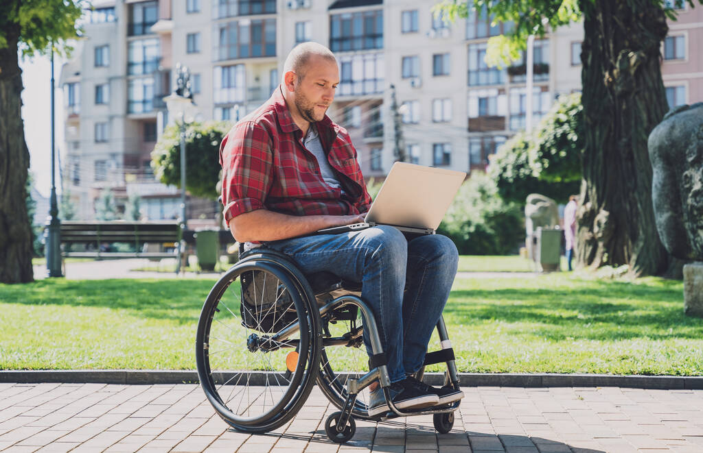 Ελεύθερος επαγγελματίας με σωματική αναπηρία σε αναπηρική καρέκλα που εργάζεται στο πάρκο - Φωτογραφία, εικόνα