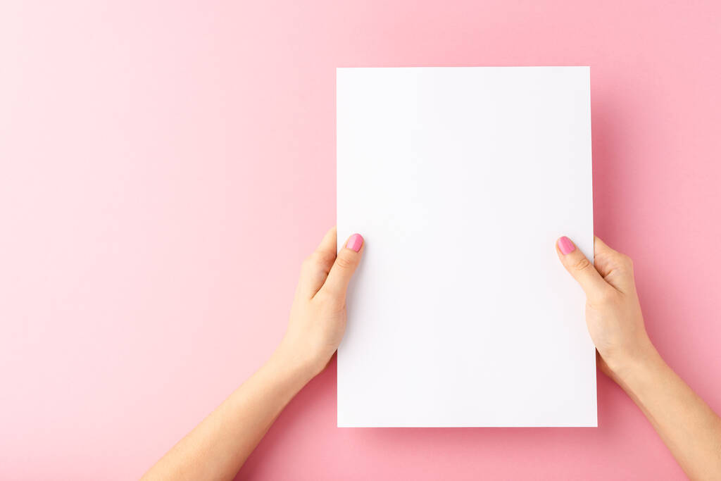 Woman hands holding empty white paper sheet on pink background. Close up - Photo, Image