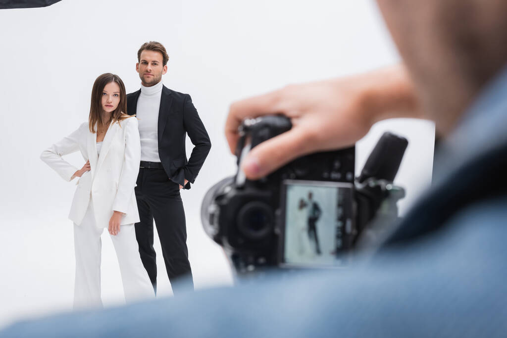 rozmazaný fotograf pracující s mladými a trendy modely pózující na bílém - Fotografie, Obrázek