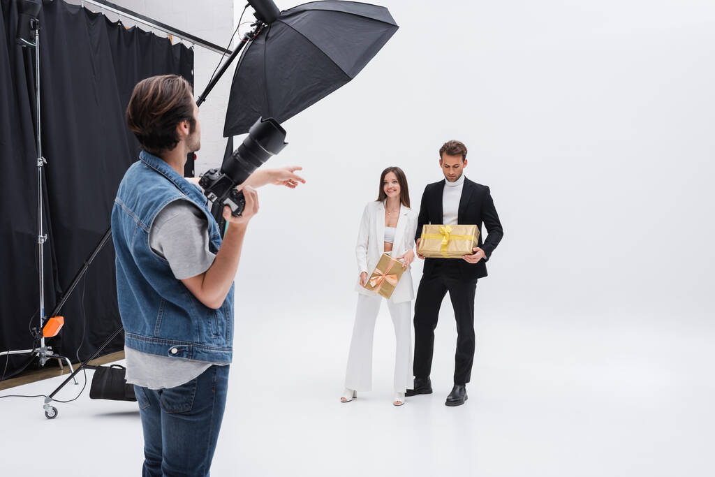 fotógrafo apontando para modelos segurando caixas de presente em branco - Foto, Imagem
