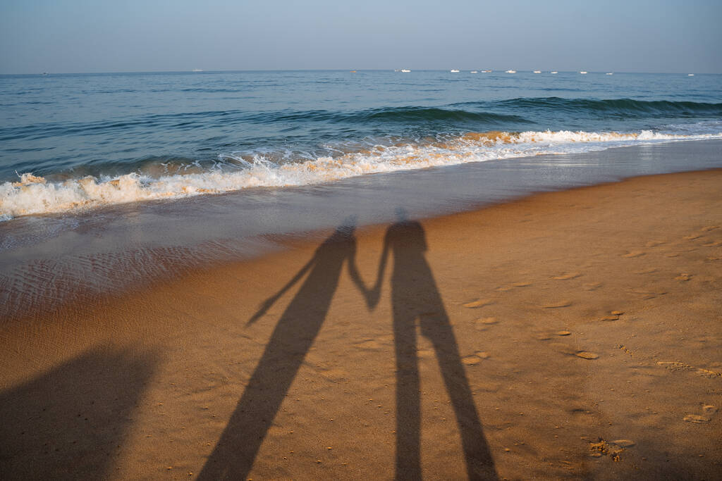 Sahilde gün batımlı bir çift. Deniz kıyısında yürü. Açık hava eğlencesi. Yüksek kalite fotoğraf - Fotoğraf, Görsel